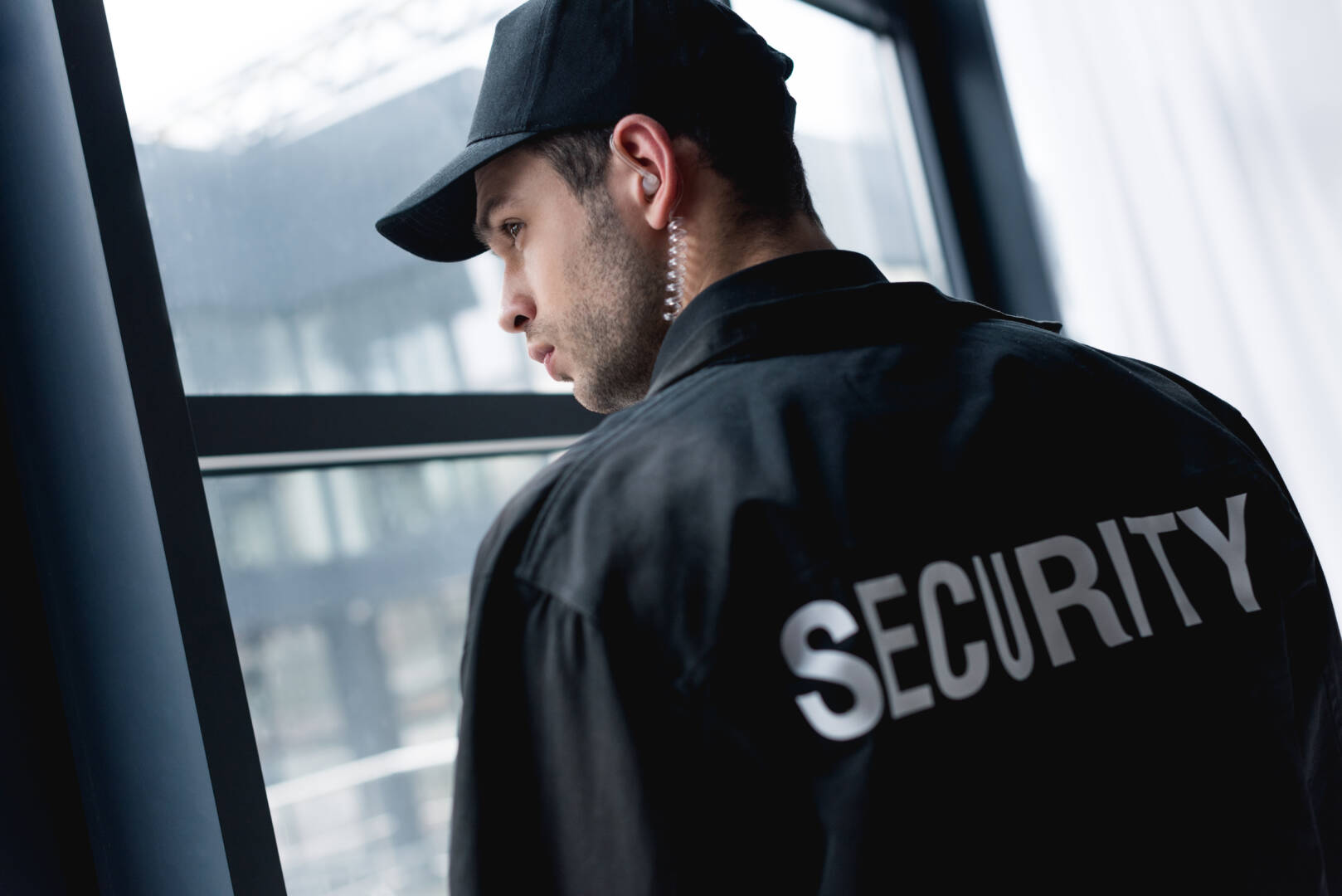 rear view of handsome guard in uniform with earphone